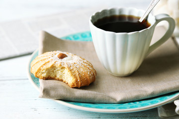Cup of coffee with tasty cookie on color wooden background