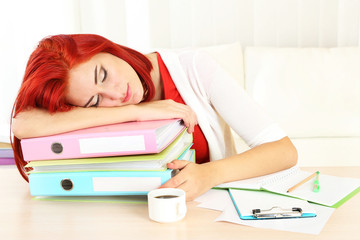 Tired girl with many folders sleeps on table