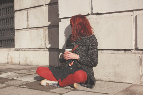 Young woman sitting in the street with coffee