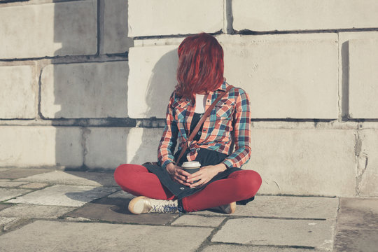 Young woman sitting in the street with coffee