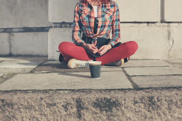 Woman sitting in street with paper cup