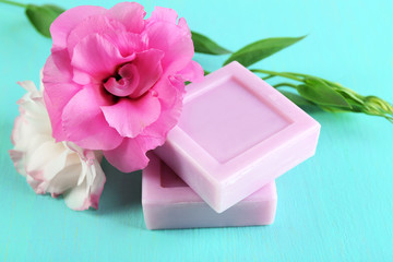 Bars of natural soap with fresh flowers on wooden background