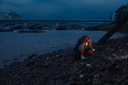 Woman beachcombing in city at night
