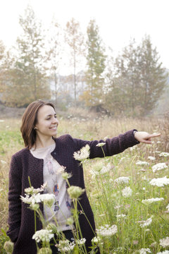 woman with coat indicating the nature on wildflowers field