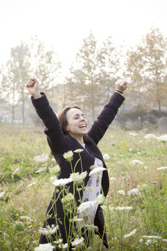 joyful girl with her arms raised in a wildflowers field