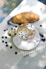 Cup of coffee with cute drawing on table, close up