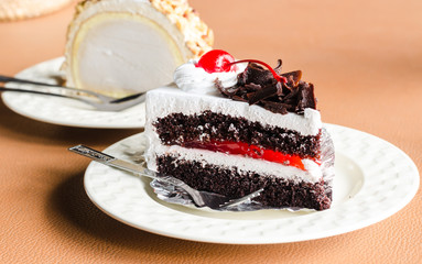 Piece of cake chocolate and cherry topping on white dish