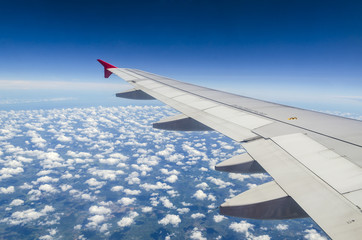 Obraz premium Wing of airplane flying above the clouds in the sky