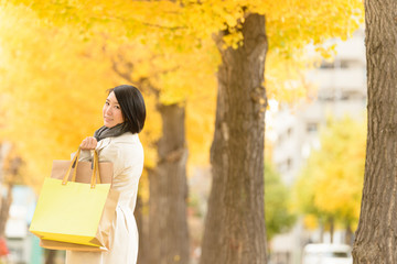 イチョウ並木を歩く女性