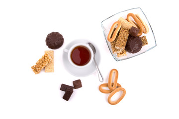 white cup of tea and a selection of sweets on a white background