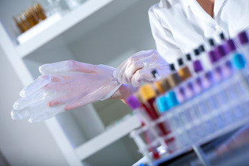 Female laboratory assistant puts protective gloves
