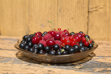 cherry currants raspberries in a glass dish on a wooden table