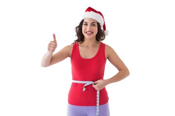 Festive fit brunette measuring her waist