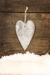 Romantisches Holzherz mit Schnee und Hintergrund aus Holz