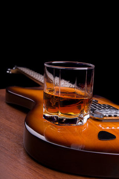 Glass of rum and plectrum on the electric guitar