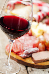 Glass of red wine with charcuterie assortment on the background