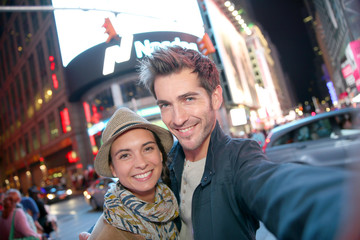 Couple standing in Time Square quarter by night