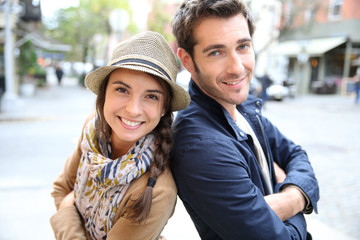 Cheerful couple standing in shopping street in fall season