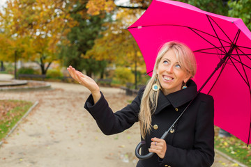 Woman with pink umbrella enjoying rainy autumn weather