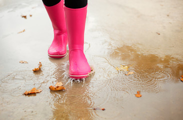 Woman with pink rubber boots walking through puddle