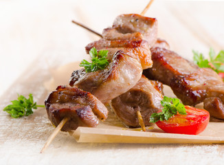 Pork kebabs served with vegetables on wooden table