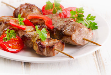 Pork kebabs served with vegetables on a white plate