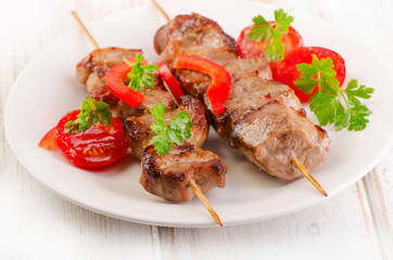 Pork kebabs served with vegetables on  white plate