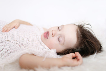 Obraz na płótnie Canvas portrait of 2 years child sleeping on white fur plaid