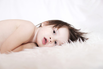 Obraz na płótnie Canvas portrait of 2 years lovely child lying on white fur rug