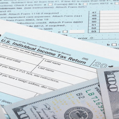 US Tax Form 1040 with 100 US dollar bills
