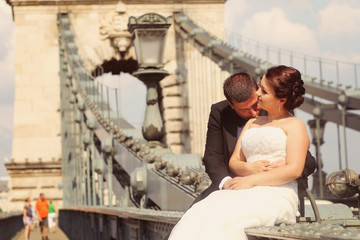 Obraz na płótnie Canvas Bride and groom having fun on a bridge in Budapest, Hungary
