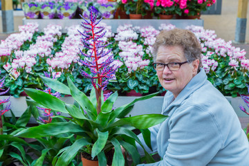 Senior woman showing flowering plant in shop