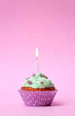 Delicious birthday cupcake on table on pink background