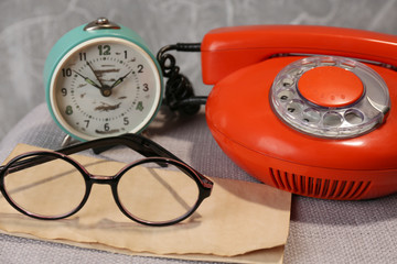 Fototapeta premium Retro phone, clock and glasses on table in room