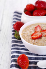 Tasty oatmeal with strawberry on table close-up
