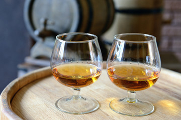 Glasses of brandy in cellar with old barrels