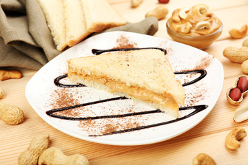 Bread slices with creamy peanut butter on wooden table