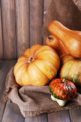 Pumpkins on sackcloth on wooden table on wooden wall background