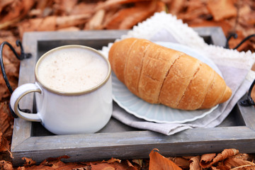 Cup of tasty hot drink and fresh croissant