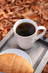 Cup of tasty hot drink and fresh croissant