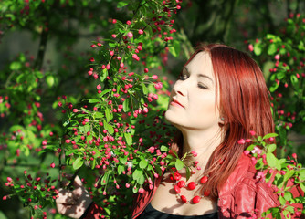 Young redhead woman enjoying cherry blossom
