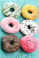 Delicious donuts with glaze on colorful wooden background