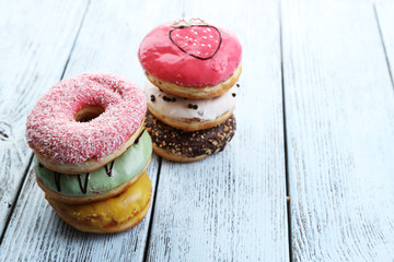 Delicious donuts with glaze on colorful wooden background