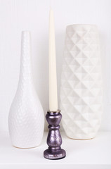 Candles in candle holders and vases on table on light