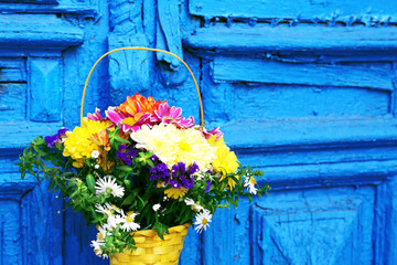 Flowers in basket on wooden door background