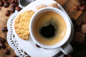Cup of coffee and tasty cookie on wooden background