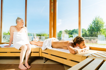 Seniorin und junge Frau schwitzen in Sauna