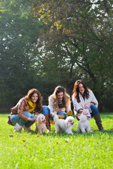 Obraz premium Three young woman with their pet dogs in the park