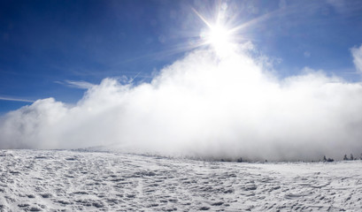Winter landscape with snow covered hill and blue sky