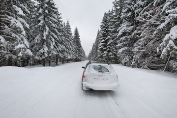 snow covered car on the winter road in forest